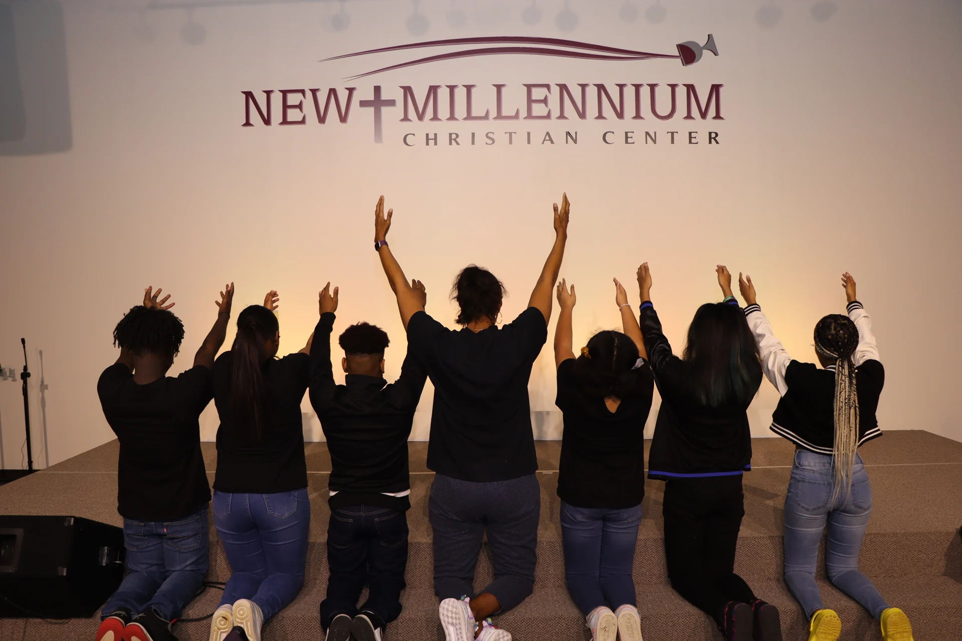 A group kneeling with raised hands inside NMCC
